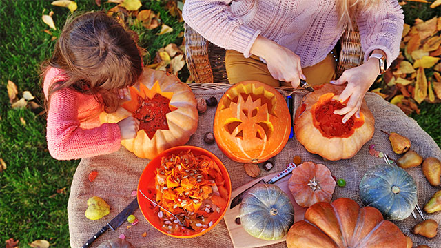 Child with a parent carving a pumpkin